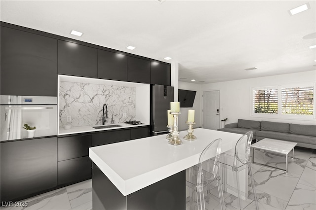 kitchen with sink, stainless steel fridge, a center island, decorative backsplash, and oven