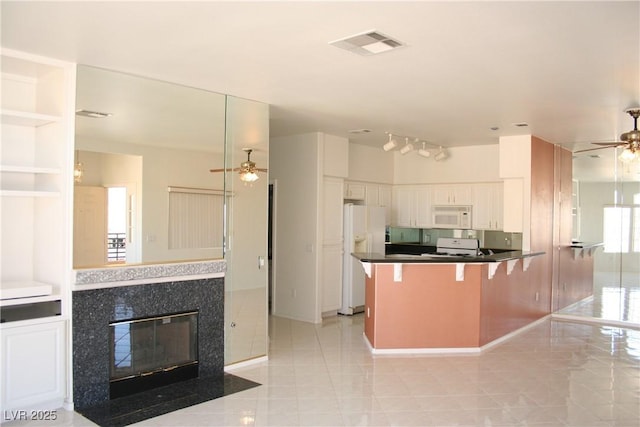 kitchen with a kitchen bar, white cabinetry, ceiling fan, kitchen peninsula, and white appliances