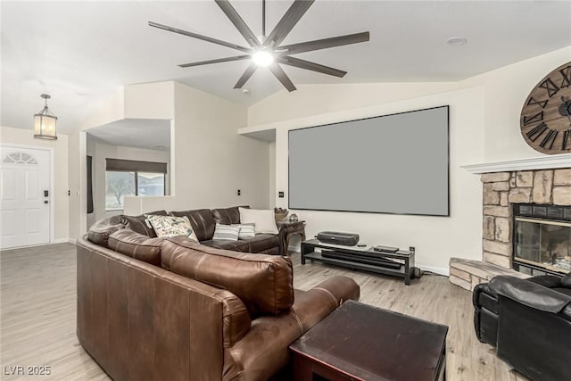 cinema room with light hardwood / wood-style flooring, ceiling fan, vaulted ceiling, and a fireplace