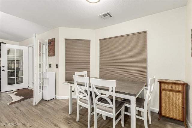 dining space with wood-type flooring and french doors