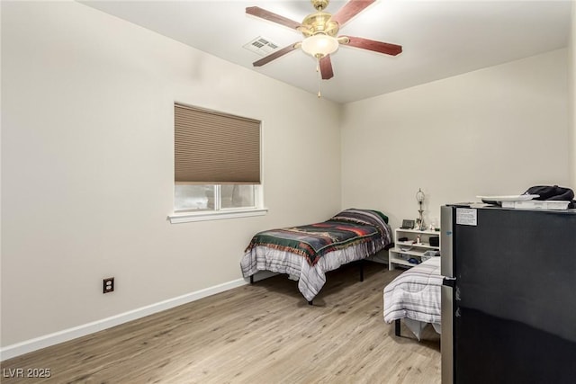 bedroom featuring ceiling fan, stainless steel fridge, and light hardwood / wood-style floors