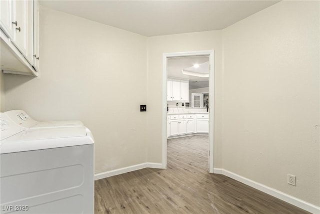 washroom with washing machine and dryer, cabinets, and hardwood / wood-style floors