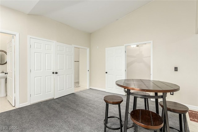 carpeted dining space featuring lofted ceiling