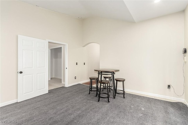 dining space with vaulted ceiling and dark colored carpet