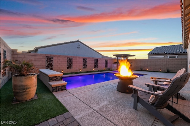 pool at dusk featuring a fire pit, pool water feature, and a patio area