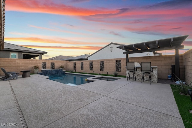 pool at dusk featuring an in ground hot tub, an outdoor bar, and a patio area