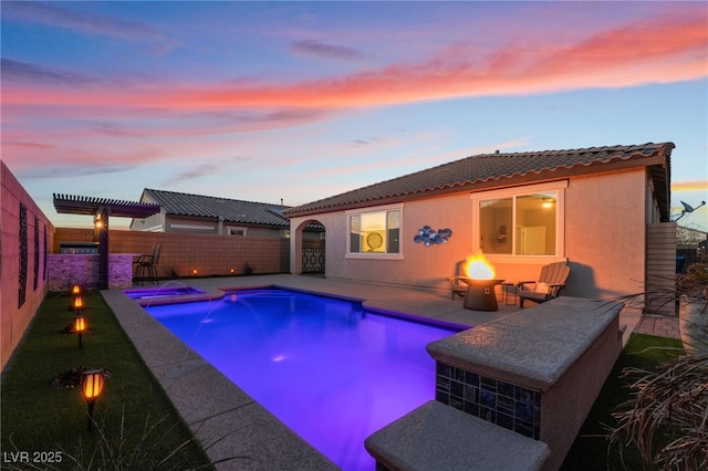 pool at dusk featuring a pergola, a fire pit, and pool water feature