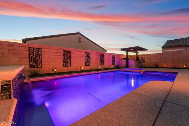 pool at dusk featuring a patio area and pool water feature