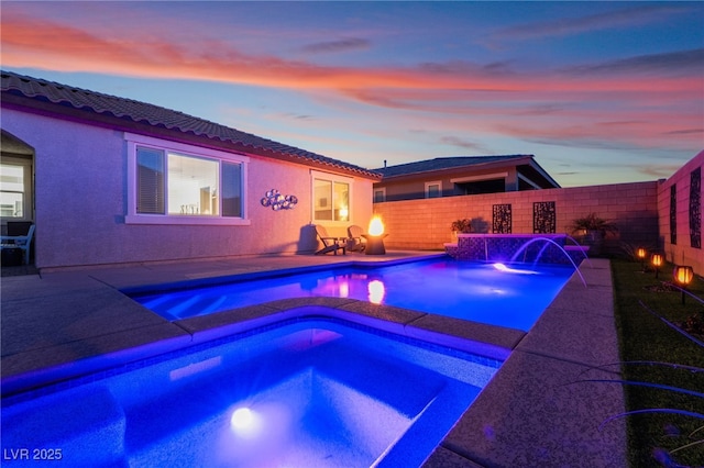 pool at dusk featuring an in ground hot tub