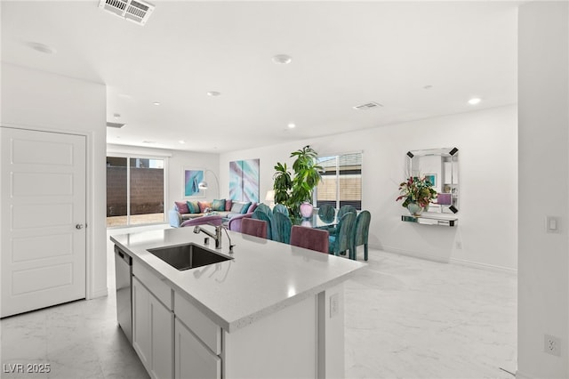 kitchen featuring an island with sink, dishwasher, sink, and light stone countertops