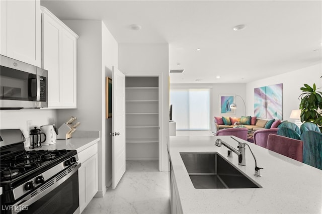 kitchen featuring light stone counters, appliances with stainless steel finishes, sink, and white cabinets