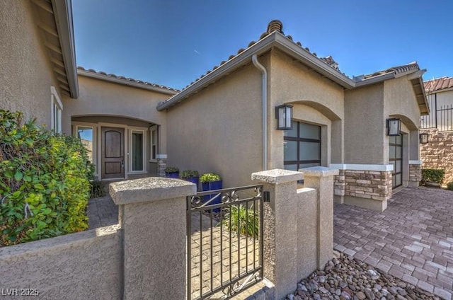 view of front of home featuring stone siding, a fenced front yard, a gate, and stucco siding