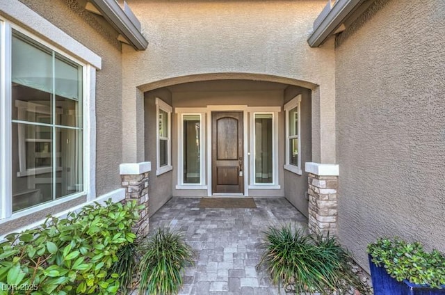 property entrance featuring stone siding and stucco siding