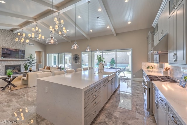 kitchen with a glass covered fireplace, a spacious island, decorative light fixtures, marble finish floor, and a sink