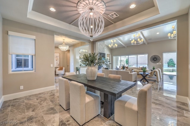 dining area featuring a chandelier, a tray ceiling, visible vents, and baseboards