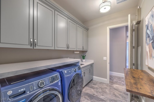 clothes washing area featuring visible vents, washer and clothes dryer, cabinet space, and baseboards