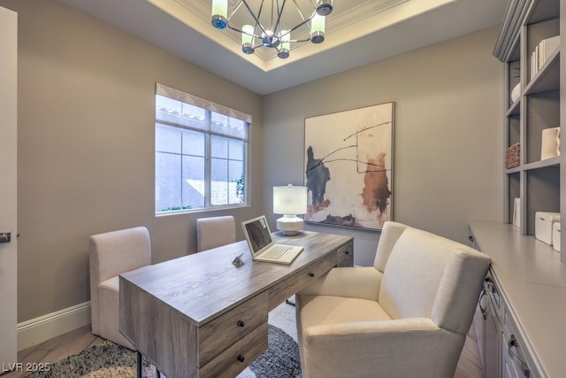 home office with baseboards, a tray ceiling, light wood-style flooring, and a notable chandelier