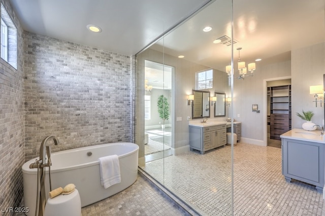 full bathroom featuring tile walls, visible vents, vanity, tile patterned flooring, and a freestanding tub