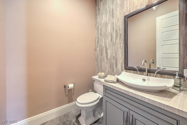 bathroom with toilet, baseboards, and vanity