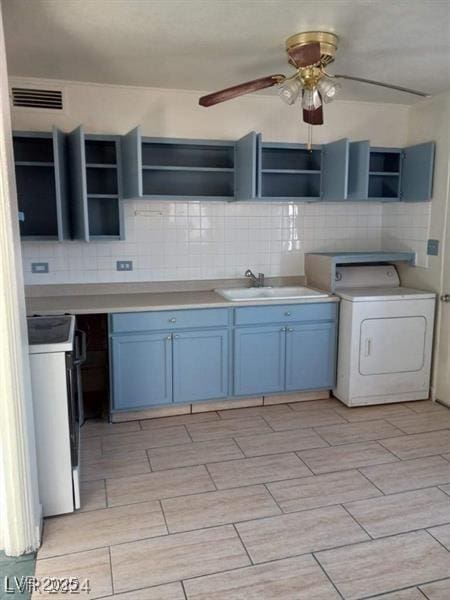 kitchen featuring blue cabinets, backsplash, washer / dryer, and white range with electric cooktop