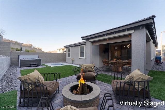 rear view of house with a fire pit, a patio area, and a hot tub