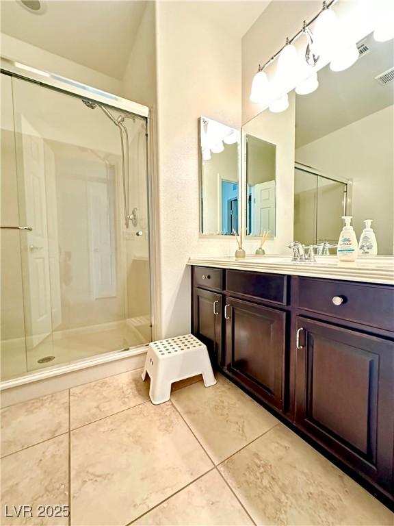 bathroom featuring vanity, a shower with shower door, and tile patterned floors