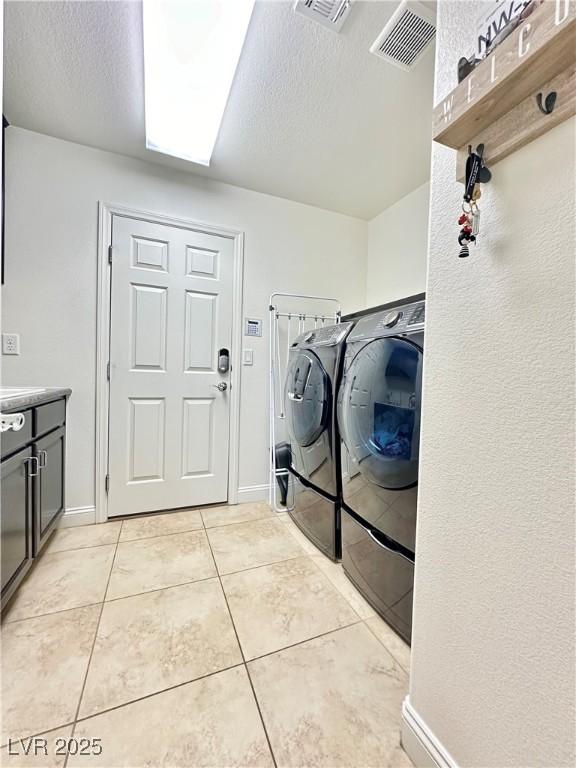 washroom with light tile patterned flooring, separate washer and dryer, and a textured ceiling