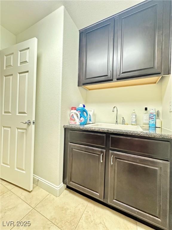 bar featuring sink, light tile patterned floors, and light stone counters