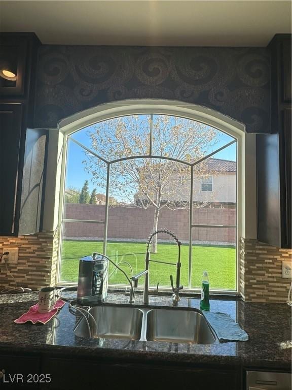 kitchen with plenty of natural light, sink, dark stone counters, and backsplash