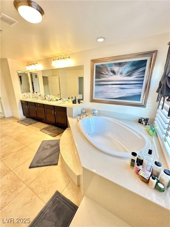 bathroom featuring tiled tub, vanity, and tile patterned floors