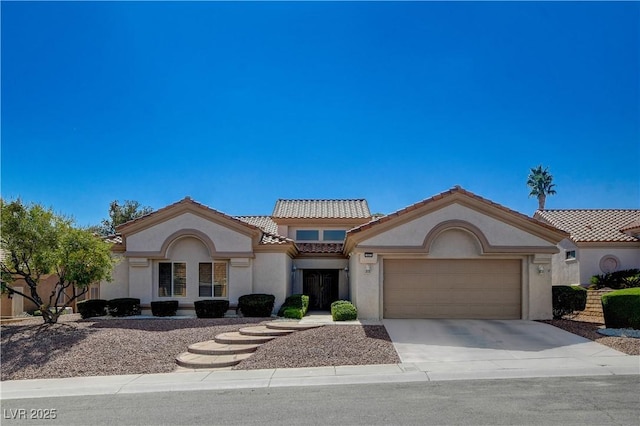 mediterranean / spanish house with a garage, driveway, a tiled roof, and stucco siding