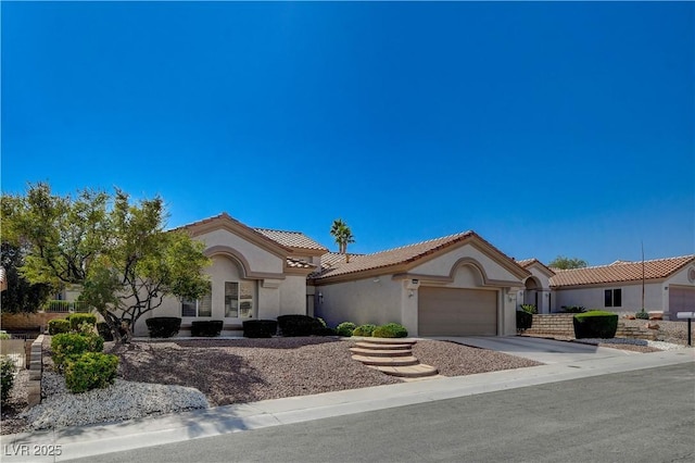 mediterranean / spanish-style house with driveway, an attached garage, a tile roof, and stucco siding