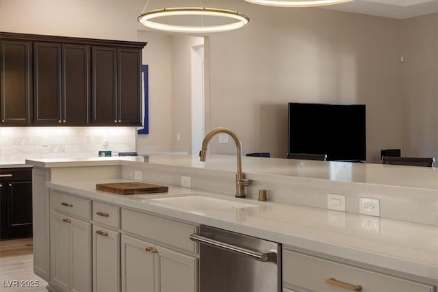 kitchen featuring pendant lighting, sink, light stone countertops, decorative backsplash, and stainless steel dishwasher