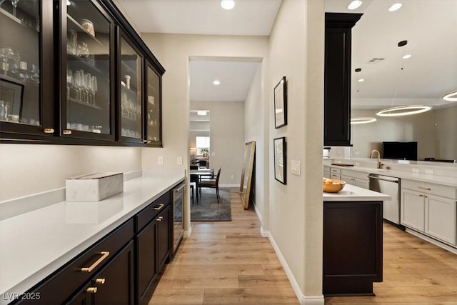 kitchen with decorative light fixtures, light hardwood / wood-style flooring, dishwasher, beverage cooler, and white cabinets