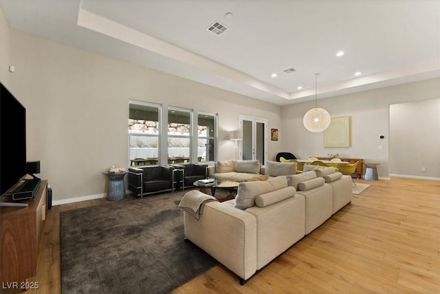 living room featuring a tray ceiling and light hardwood / wood-style floors