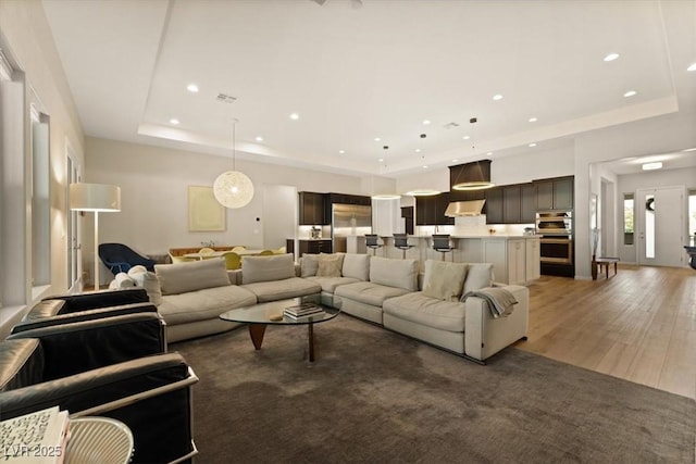 living room with a tray ceiling and dark wood-type flooring