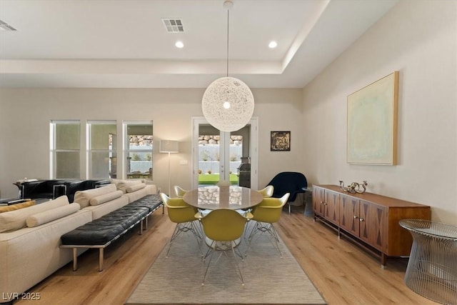 dining area featuring a tray ceiling and light hardwood / wood-style floors