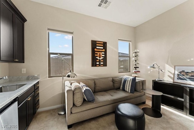 living room with plenty of natural light, sink, and light carpet