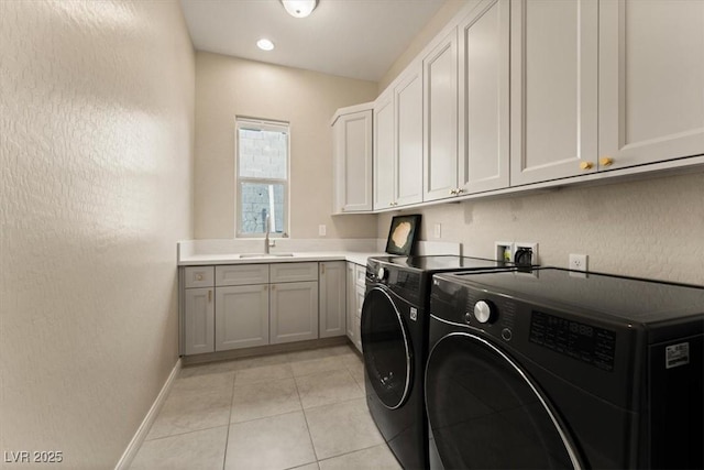 laundry area featuring cabinets, washing machine and clothes dryer, sink, and light tile patterned floors