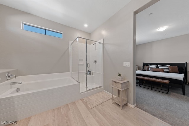 bathroom with hardwood / wood-style flooring and shower with separate bathtub