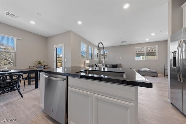 kitchen featuring sink, white cabinetry, a center island, appliances with stainless steel finishes, and a healthy amount of sunlight