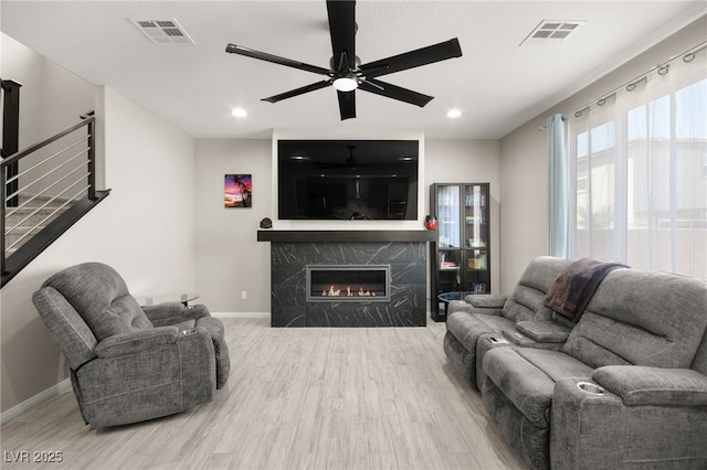 living room with ceiling fan, wood-type flooring, and a premium fireplace