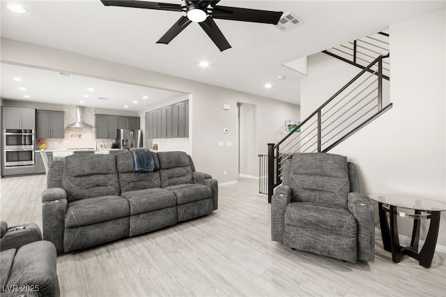 living room featuring ceiling fan, sink, and light hardwood / wood-style floors