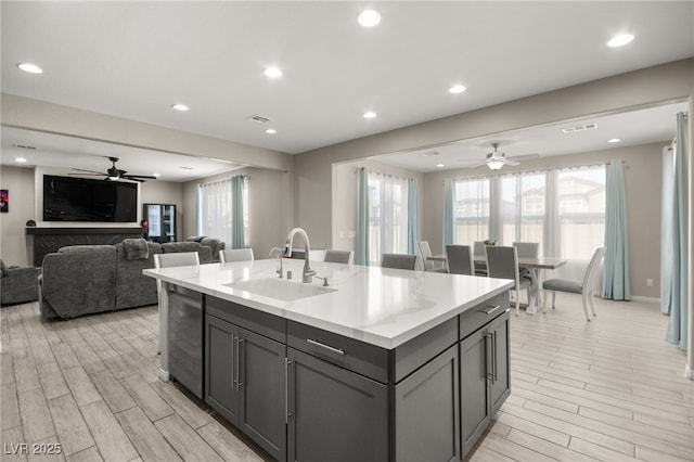 kitchen featuring gray cabinets, sink, wine cooler, ceiling fan, and a center island with sink