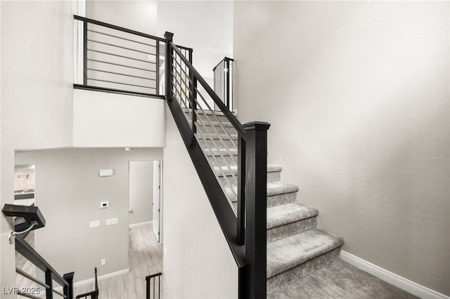 stairway with a towering ceiling and wood-type flooring