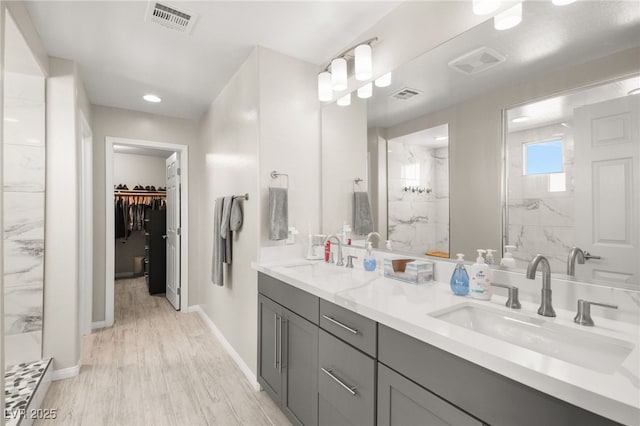 bathroom featuring hardwood / wood-style floors, vanity, and a tile shower