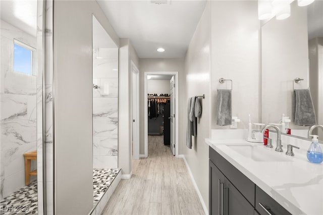 bathroom with vanity, tiled shower, and hardwood / wood-style floors