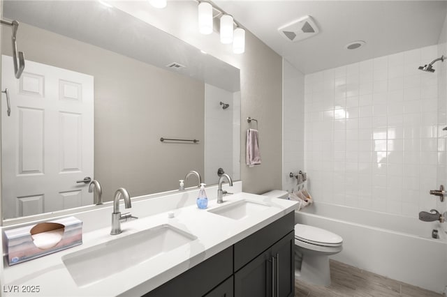 full bathroom with tiled shower / bath combo, wood-type flooring, vanity, and toilet