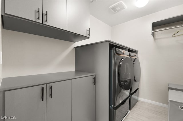 clothes washing area with separate washer and dryer and cabinets