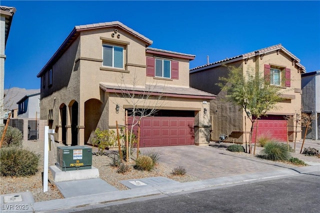 view of front facade featuring stucco siding, decorative driveway, a garage, and fence